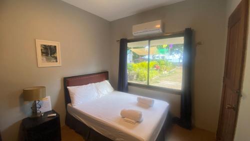 a small bedroom with a bed with a window at Seaside traveler's Inn by Camiguin Island Home in Catarman