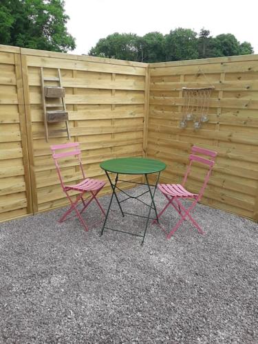 two pink chairs and a table with a green table at Gite cosy ,2 personnes, 5km Bayeux in Nonant