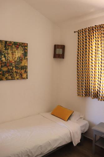 a bedroom with a bed and a window with a curtain at Résidence U Pirellu in Porto-Vecchio
