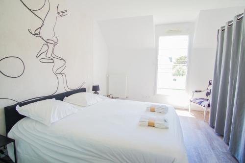 une chambre avec un lit blanc avec une fresque de branche sur le mur dans l'établissement -FULL- Magnifique T3, terrasse vue mer et garage, à Concarneau