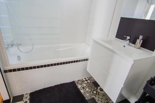 une salle de bain blanche avec une baignoire et un lavabo dans l'établissement -PICCO VERDE- Appartement avec balcon - Concarneau, à Concarneau