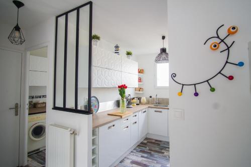 une cuisine avec des armoires blanches et une laveuse et une sécheuse dans l'établissement -SKOL- Charmant T2, proche du centre de Concarneau, à Concarneau