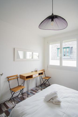- une chambre avec un lit et un bureau avec deux chaises dans l'établissement -SKOL- Charmant T2, proche du centre de Concarneau, à Concarneau