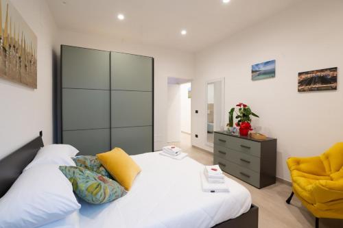 a bedroom with a white bed and a yellow chair at Da Zia Gina Locazione Turistica in Bisceglie