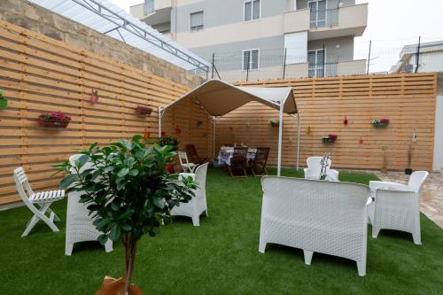 a patio with white chairs and a table and a tree at Da Zia Gina Locazione Turistica in Bisceglie