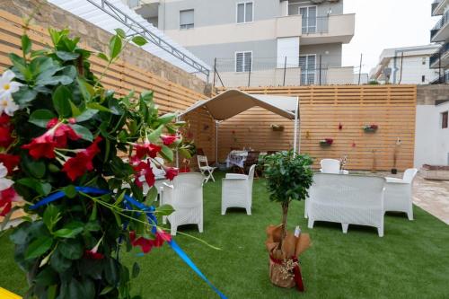 a patio with white chairs and a table and some flowers at Da Zia Gina Locazione Turistica in Bisceglie