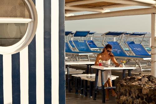 a woman sitting at a table in front of the ocean at Grand Hotel Il Moresco in Ischia
