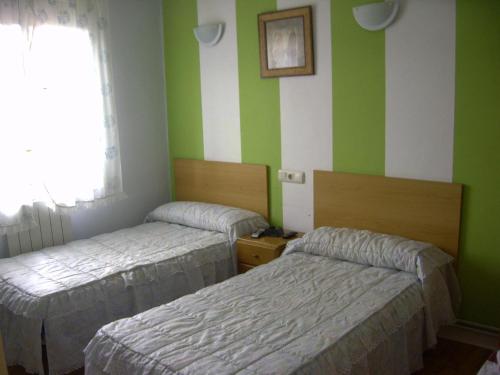 two beds in a room with green and white stripes at Pensión Gema in Irún