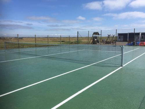 a tennis net on a tennis court with a playground at Agger Tange Feriecenter lejligheder - 100 m fra Vesterhavet in Vestervig