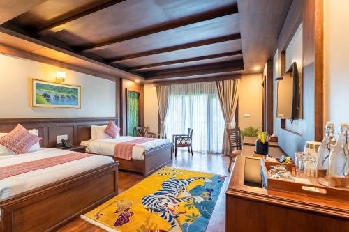 a hotel room with two beds and a table at River Bank Jungle Resort, Chitwan in Bharatpur
