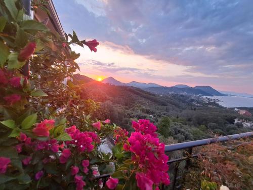 a view of the sunset from a balcony with pink flowers at 75 Steps Apartments in Mesongi