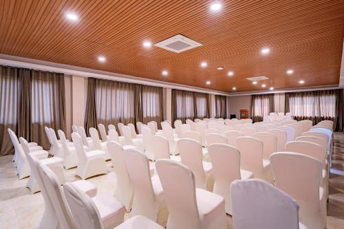 an empty room with white chairs and tables at River Bank Jungle Resort, Chitwan in Bharatpur