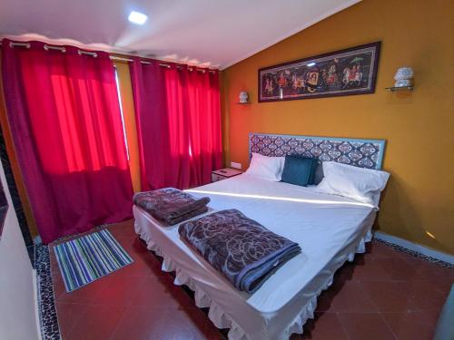 a bedroom with a large bed with red curtains at Kutch Leela Resort in Mandvi