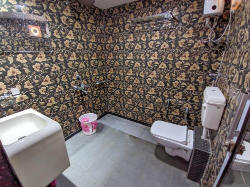 a bathroom with a sink and a toilet and wallpaper at Kutch Leela Resort in Mandvi