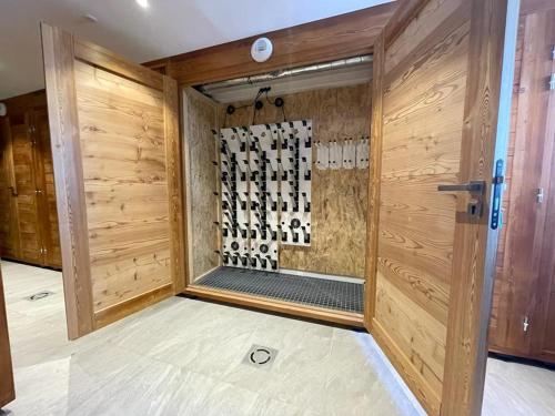 - une douche dans une chambre dotée d'un mur en bois dans l'établissement Chalet Monthabor, à La Toussuire
