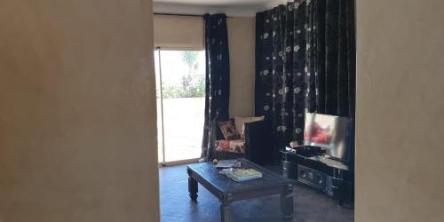 a living room with a table and a tv at Maison d'Hôtes à Marrakech in Marrakech