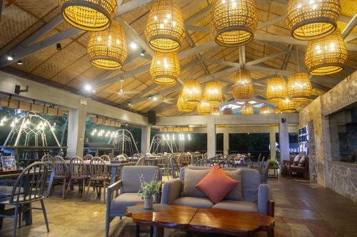 un restaurante con mesas, sillas y lámparas de araña en Fairways and Bluewater Boracay en Boracay