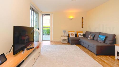 a living room with a couch and a flat screen tv at Coastal Garden Apartment with Sea Views By Adliv in Birchington