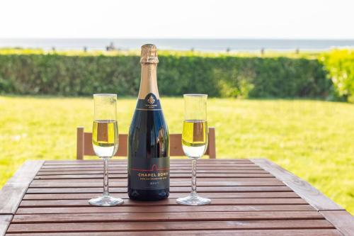 a bottle of wine sitting on a table with two glasses at Coastal Garden Apartment with Sea Views By Adliv in Birchington