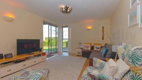 a living room with a couch and a tv at Coastal Garden Apartment with Sea Views By Adliv in Birchington