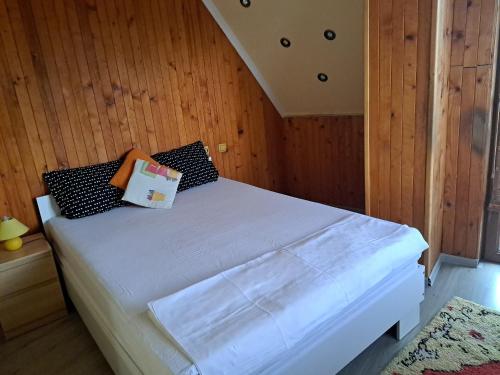 - une chambre avec un lit blanc et des murs en bois dans l'établissement Морска звезда Апартамент, à Bourgas