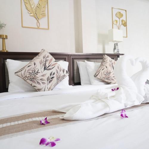 zwei Betten mit weißen Laken und lila Blumen darauf in der Unterkunft ATC Residence in Bang Su