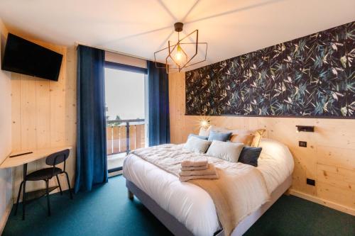 a bedroom with a large bed and a desk at Le Col Panoramic in La Toussuire