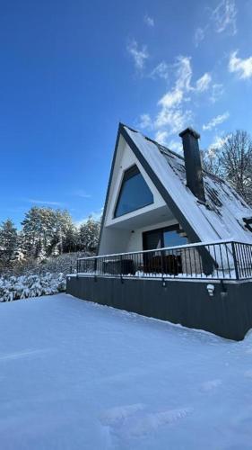 a house with a snow covered roof in the snow at Vila Hasandić in Visoko