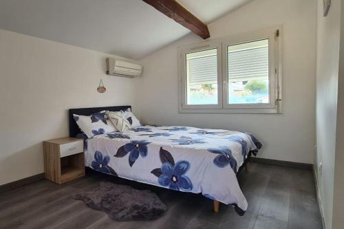 - une chambre avec un lit et une couverture de fleurs bleues dans l'établissement Appartement scandinave au soleil, à Baillargues