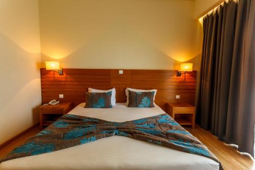 um quarto de hotel com uma cama grande num quarto em Hotel Caravelas em Madalena