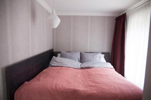 a bed with a red blanket and white pillows at Hotelli Punkaharju in Punkaharju