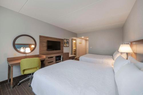 a hotel room with two beds and a desk and a mirror at Hampton Inn & Suites Burlington in Burlington