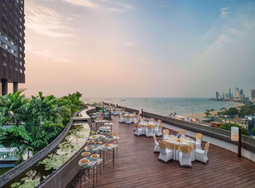 a balcony with tables and chairs and the ocean at Hilton Pattaya in Pattaya Central