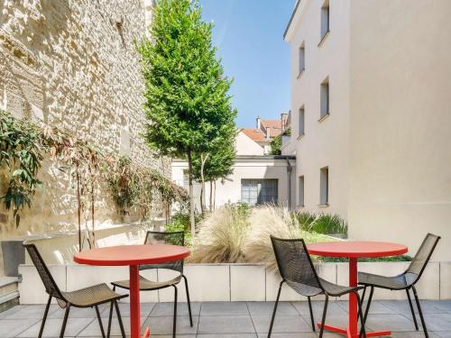 duas mesas e cadeiras vermelhas num pátio com árvores em ibis Saint Germain en Laye Centre em Saint-Germain-en-Laye