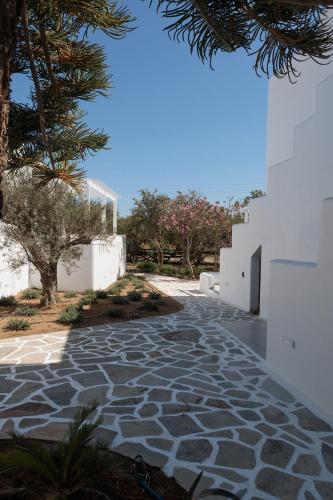 a stone walkway with trees and a white building at Agia Anna Living in Agia Anna Naxos