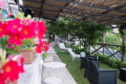 a patio with white chairs and tables and flowers at Amalfi Sky View in Scala