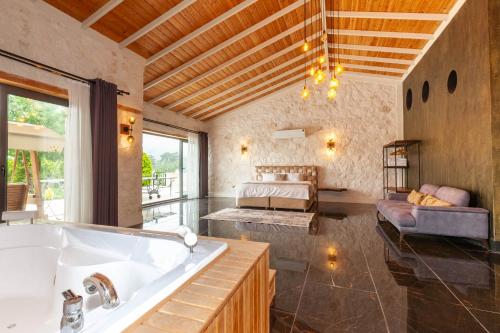 uma casa de banho com uma banheira e um quarto com uma cama em Eco Villa TOPRAK em Kalkan