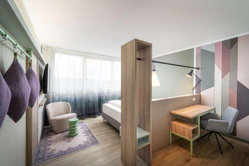 a bedroom with a bed and a desk and a chair at elaya hotel stuttgart ludwigsburg ehemals Abacco by Rilano in Korntal-Münchingen