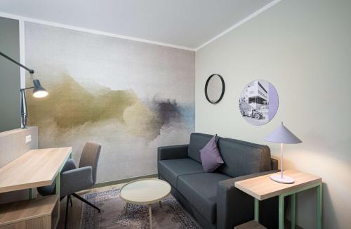 a living room with a couch and a table at elaya hotel stuttgart ludwigsburg ehemals Abacco by Rilano in Korntal-Münchingen