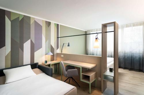 a bedroom with a bed and a desk and a table at elaya hotel stuttgart ludwigsburg ehemals Abacco by Rilano in Korntal-Münchingen