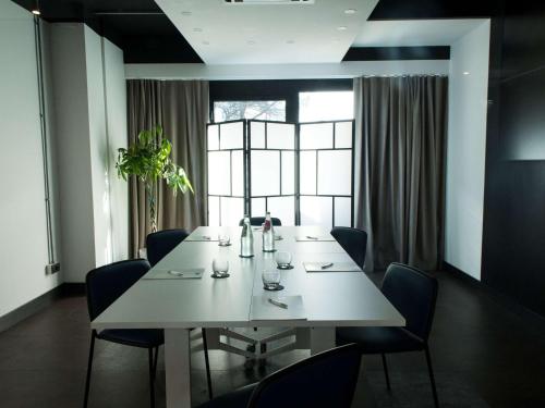 a dining room with a white table and chairs at Mercure Roma Cinecittà in Rome