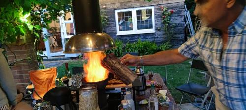 a man is cooking food on a grill at Relax and unwind at Windrush Lodge in Lydiard Millicent