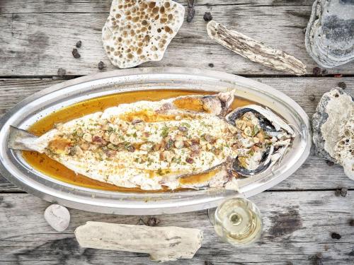 a plate of food with a fish on a table at Hotel Donibane Saint-Jean-de-Luz in Saint-Jean-de-Luz