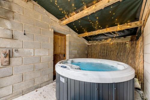 Cette chambre dispose d'un bain à remous et d'un mur en briques. dans l'établissement Malham Wellbeing 1-bed Retreat With Hot Tub, à Malham