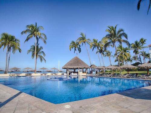 a large swimming pool with palm trees and umbrellas at Marival Emotions Resort All Inclusive - Future Mercure in Nuevo Vallarta