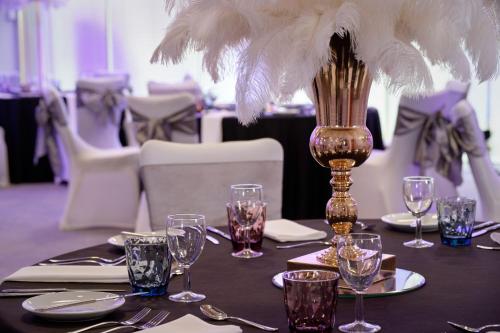 a table with glasses and a vase with feathers on it at Sheraton Heathrow Hotel in Hillingdon