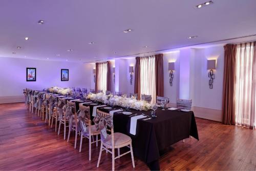 a long table in a room with tables and chairs at Sheraton Heathrow Hotel in Hillingdon