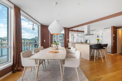 a dining room and kitchen with a table and chairs at Eksklusiv toppleilighet med det lille ekstra. in Bodø
