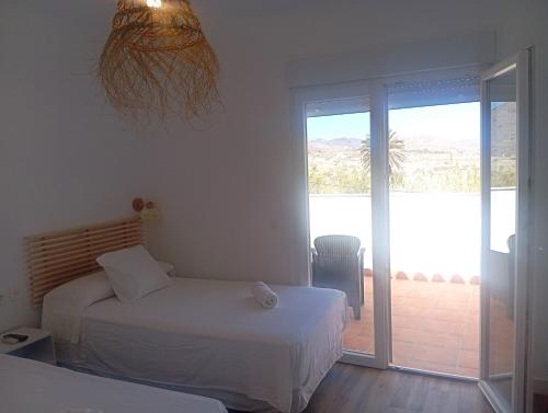 a bedroom with two beds and a sliding glass door at HOSTAL CASA EMILIO in Almería