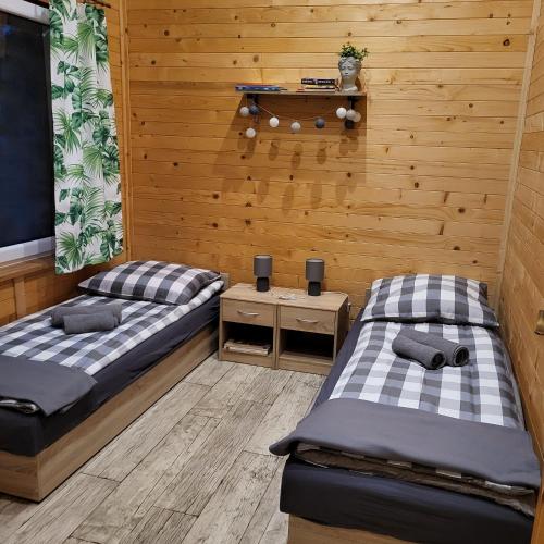 two beds in a room with wooden walls at MARWIKOWE Domki Wypoczynkowe in Sieraków